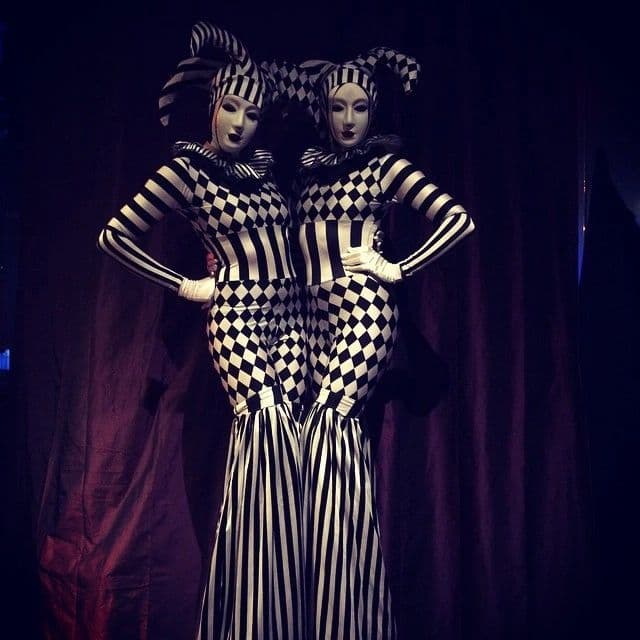 Stilt walker in black and white checkered costume entertaining guests at a circus themed gala
