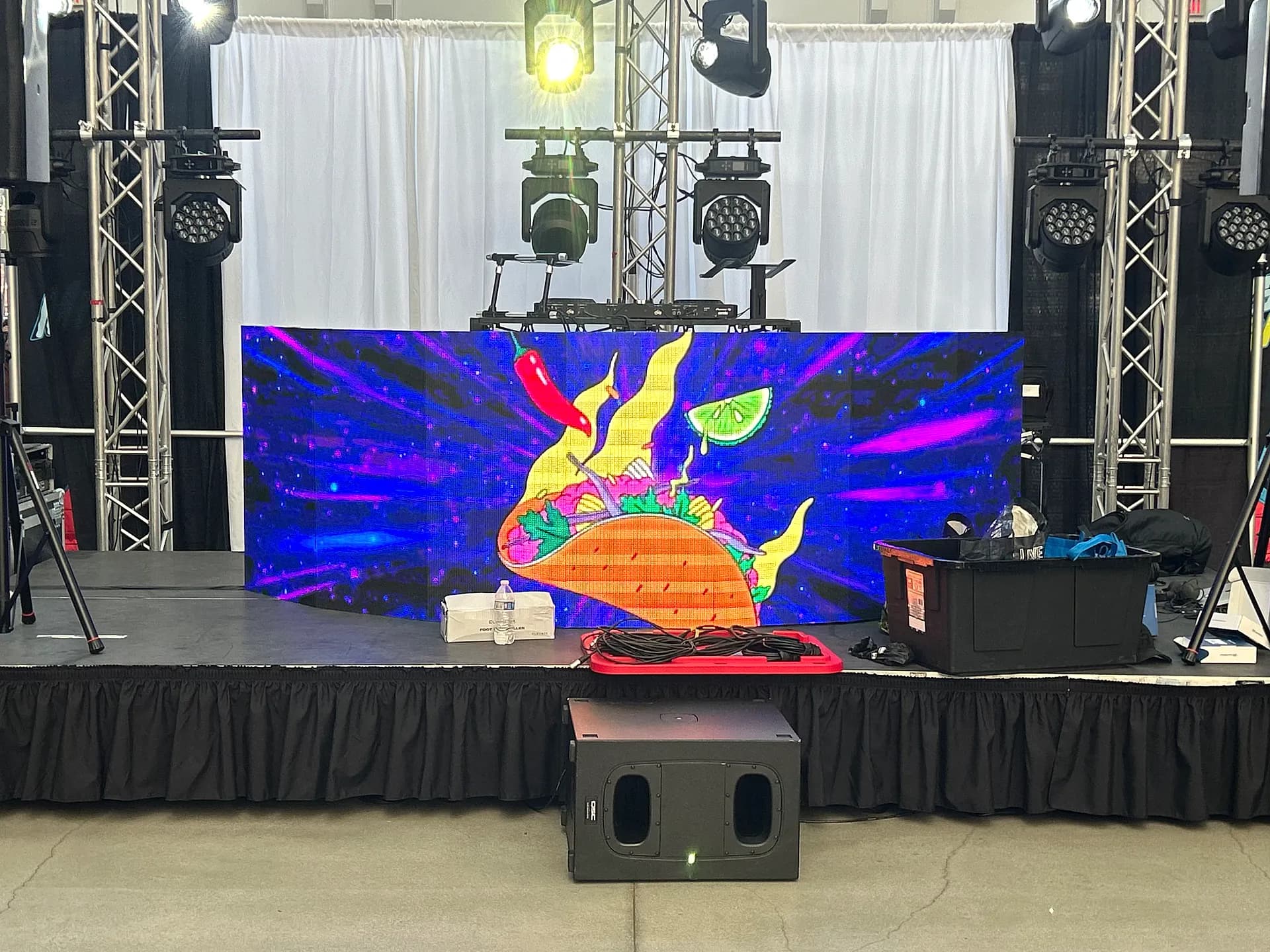 Curved LED video wall on a custom stage with moving-head lighting at a brand activation built by Nicholson Events