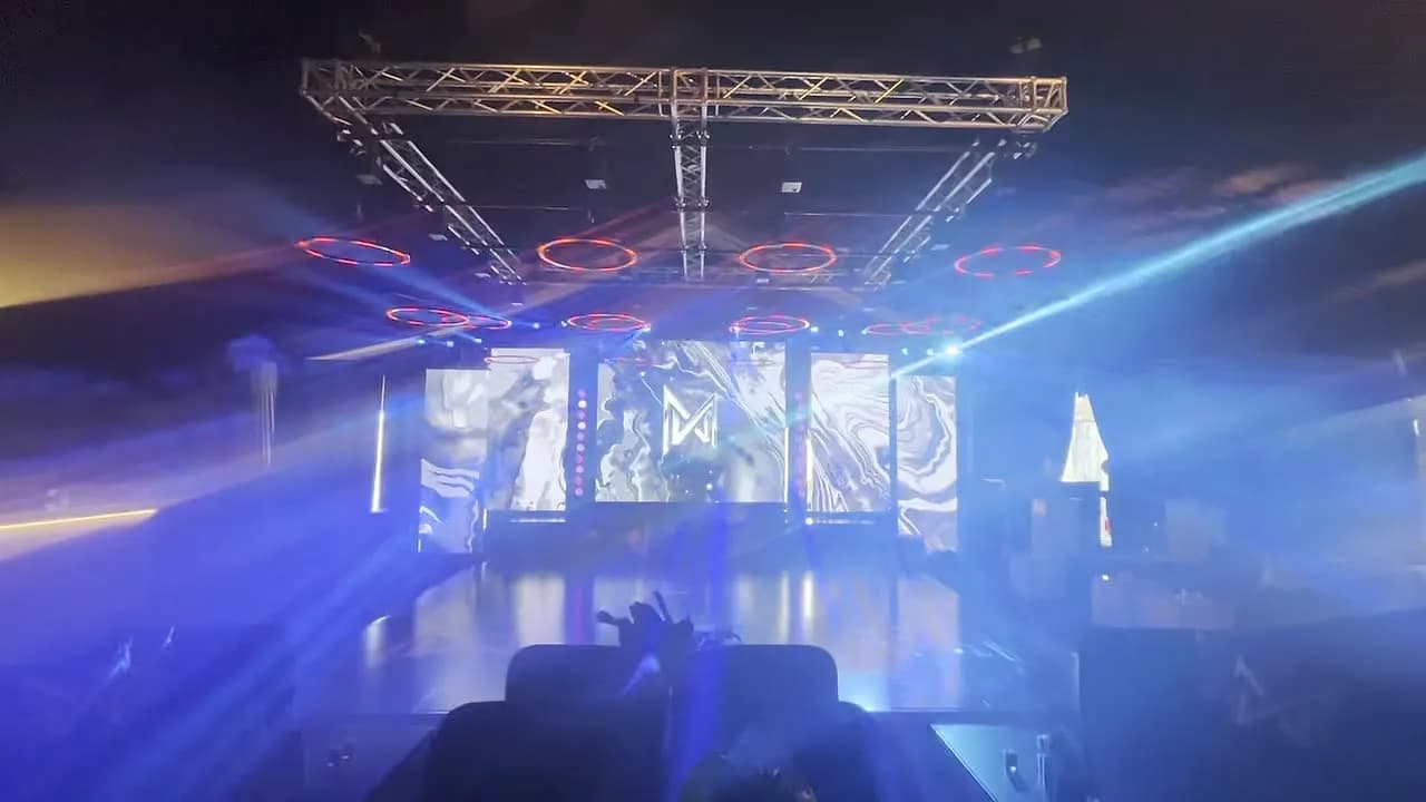 Corporate event main stage with LED video walls and intelligent blue beam lighting cutting through haze
