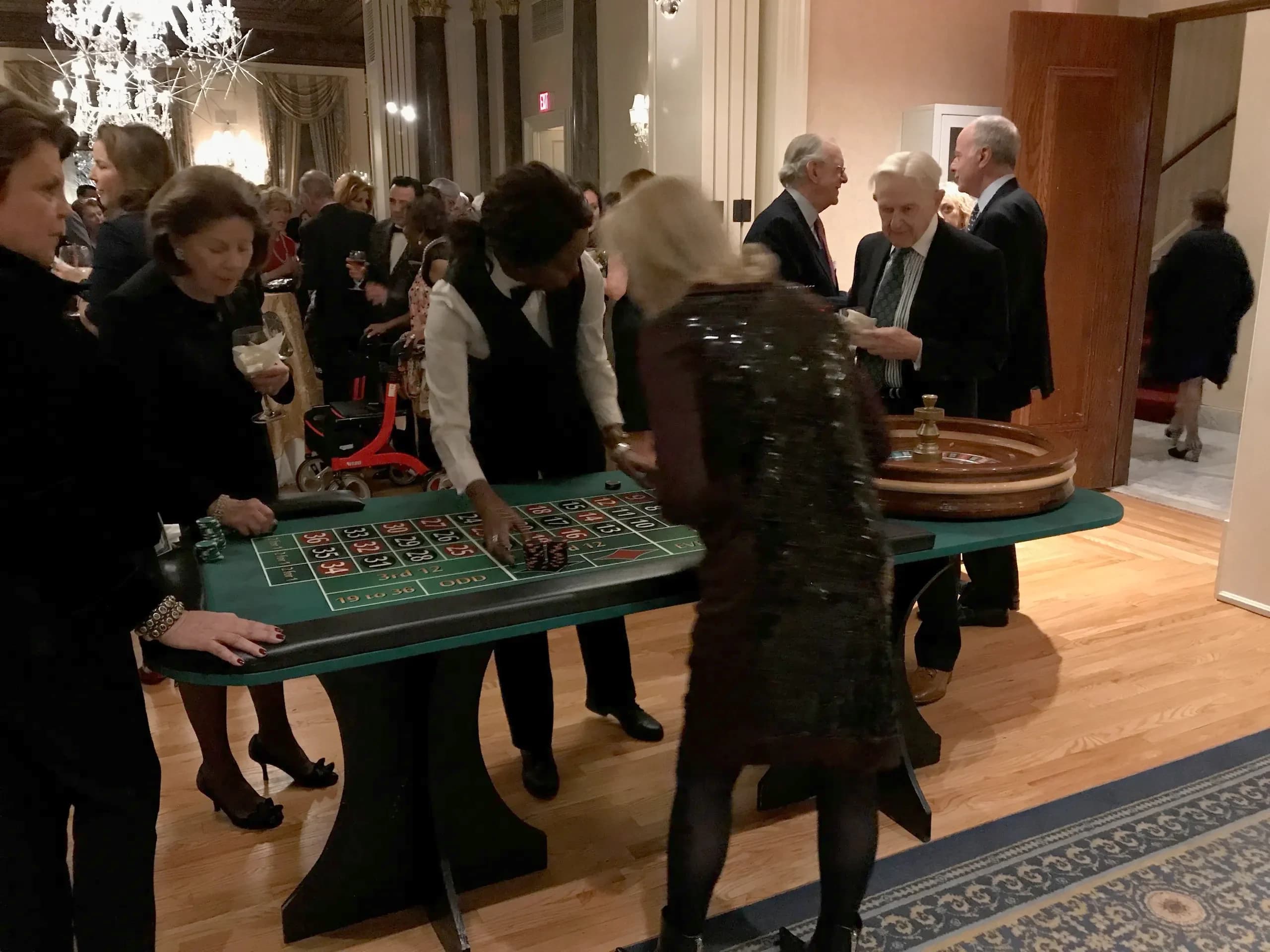 Guests in formal wear playing roulette at a black-tie casino night fundraiser