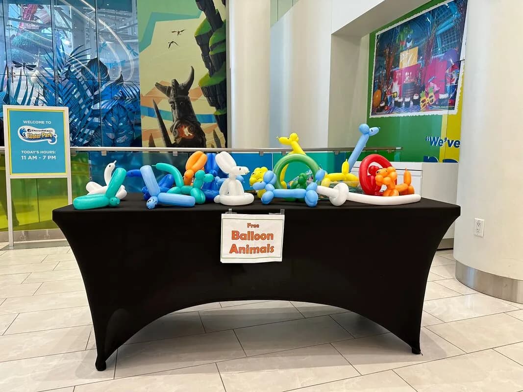 Table display of finished balloon animal sculptures with a Free Balloon Animals sign at an indoor venue