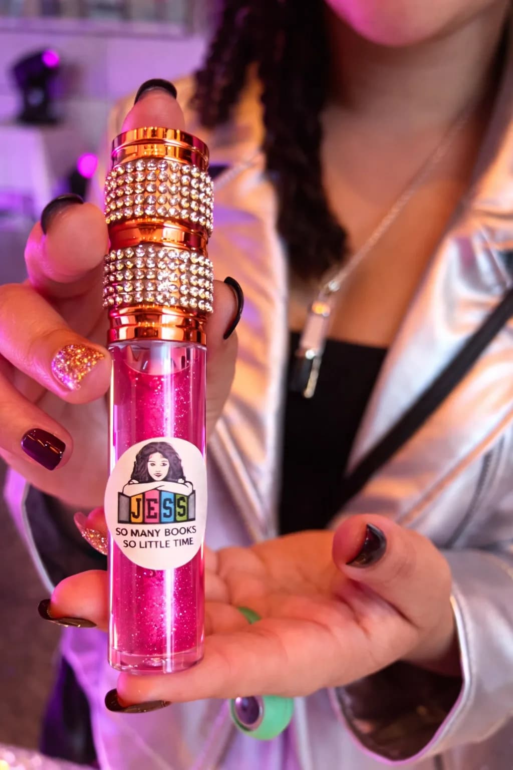 Guest holding a personalized bedazzled lip gloss tube favor with a name label from the lip gloss bar