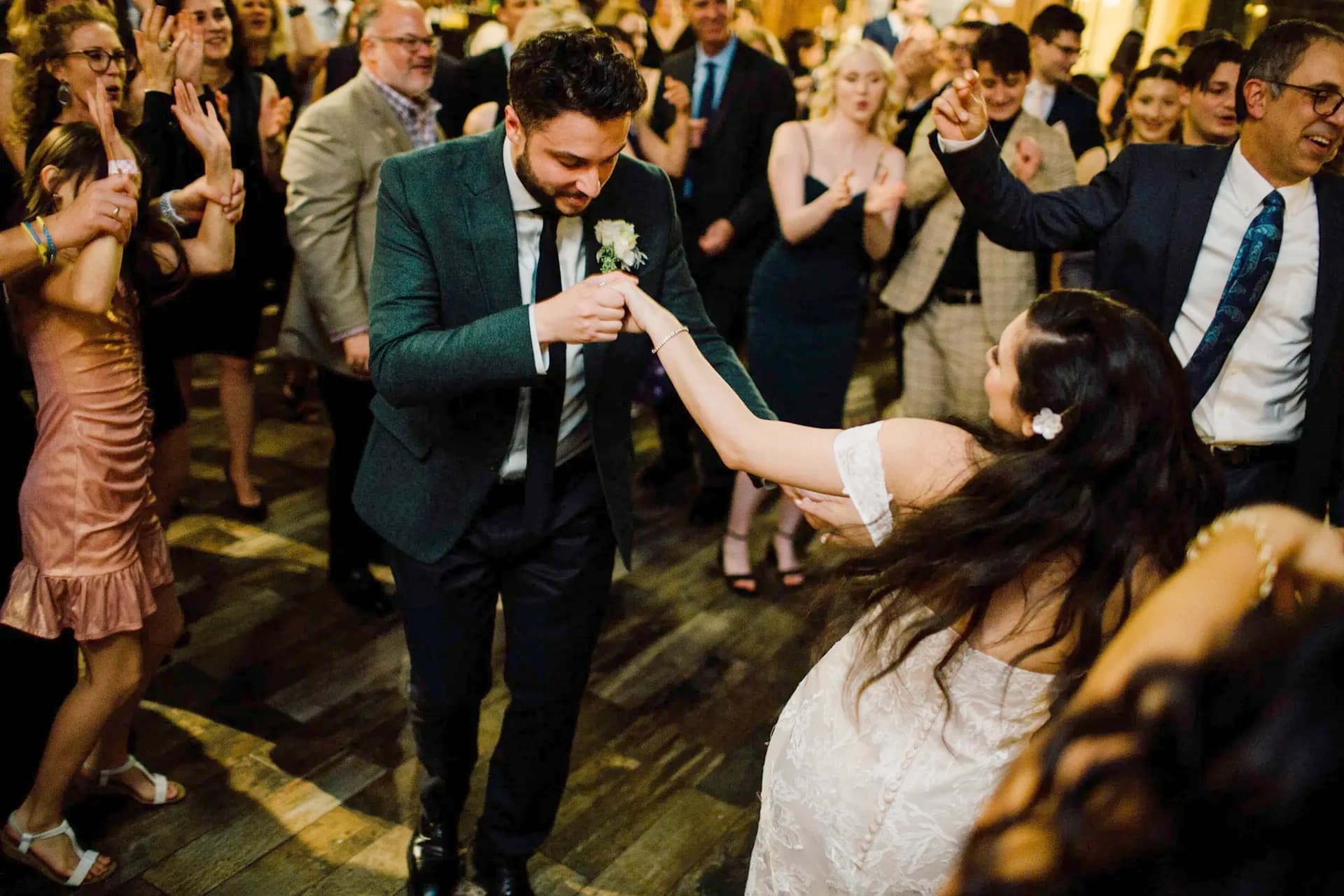 Bride and groom dancing in the center of a packed, celebrating wedding reception dance floor
