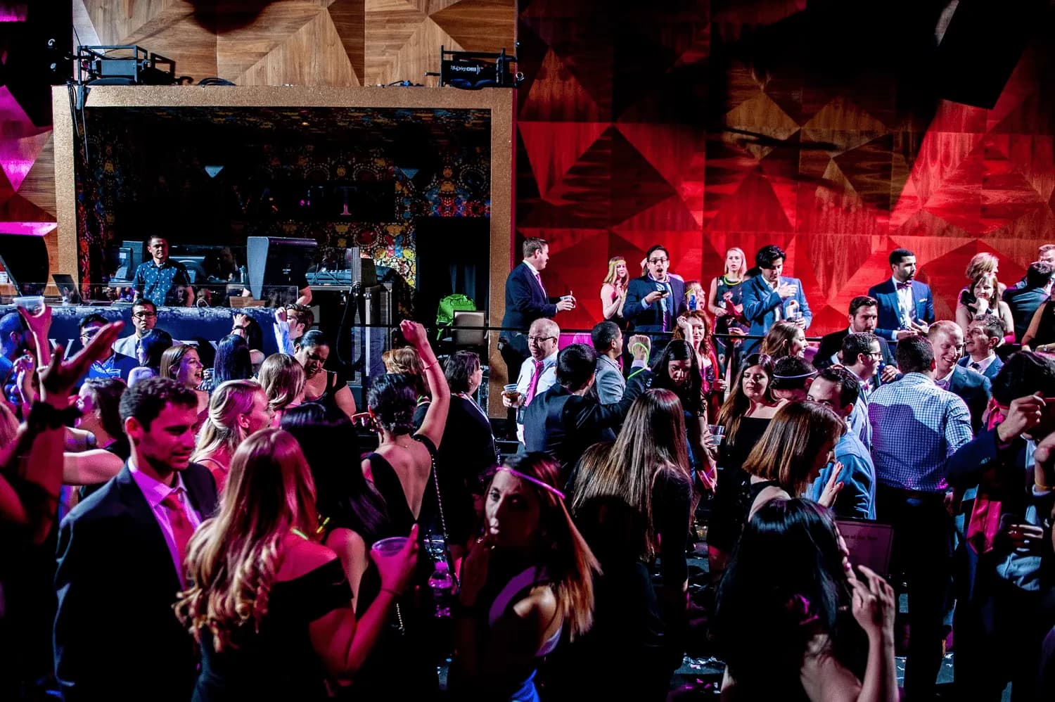 Packed dance floor under dramatic red and purple lighting at a high-end corporate event produced by Nicholson Events