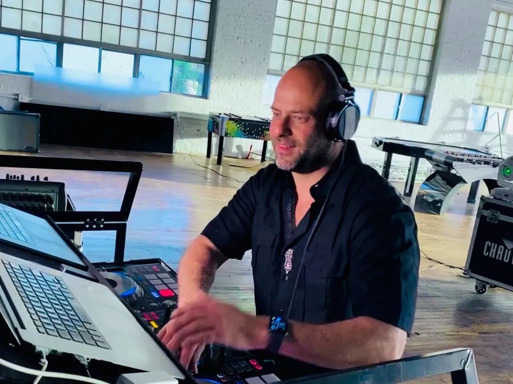 DJ Shiran Nicholson mixing at a daytime loft venue with games and production staged behind him
