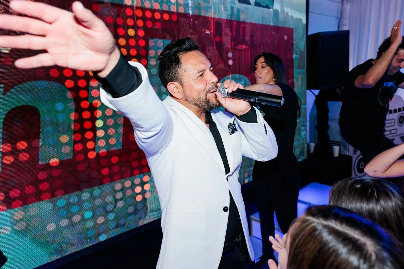 MC Nelson performing on stage with microphone raised and arm extended, LED display backdrop at a mitzvah celebration