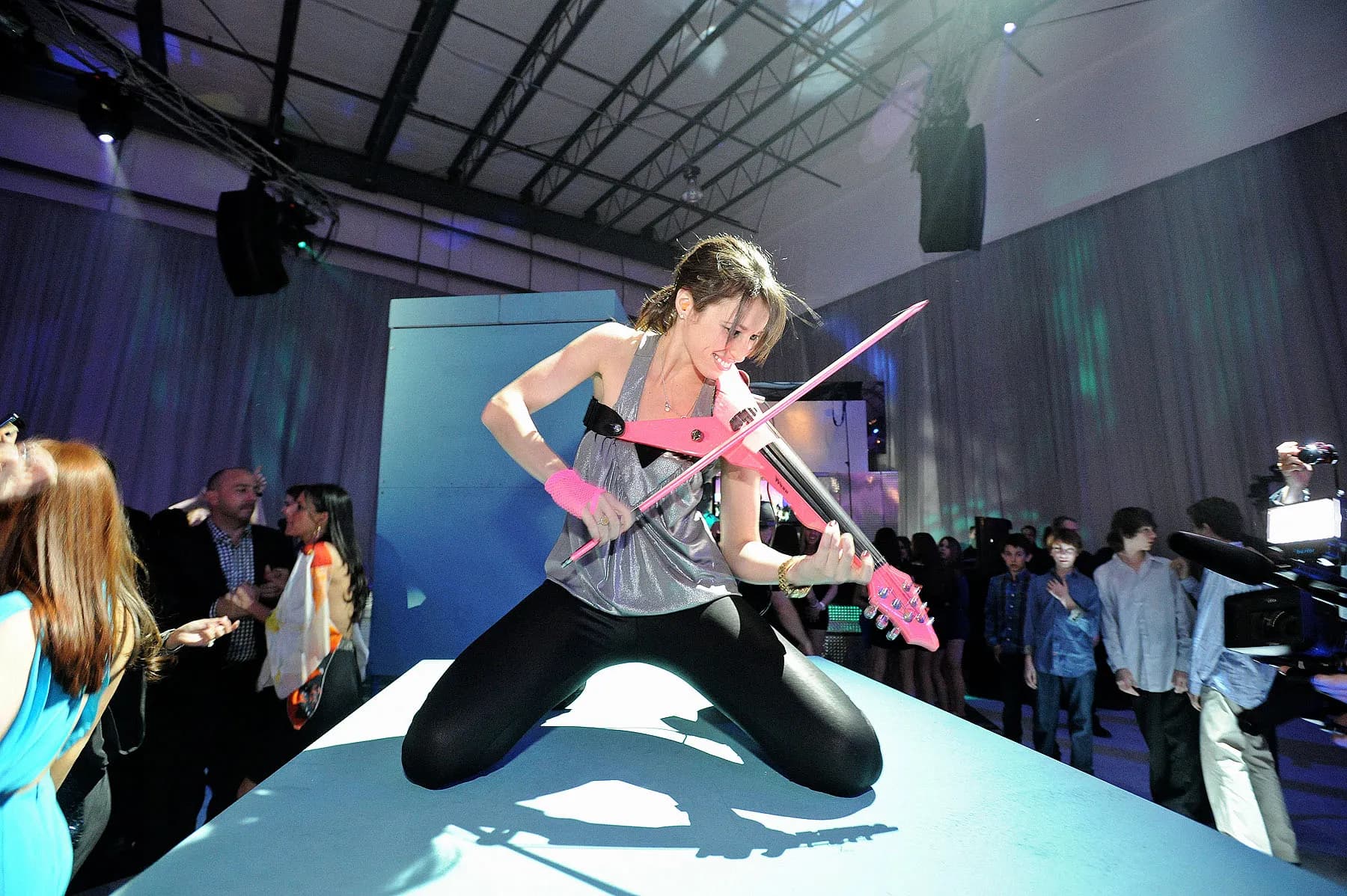 Electric violinist performing a dynamic high-energy set on a stage at an event