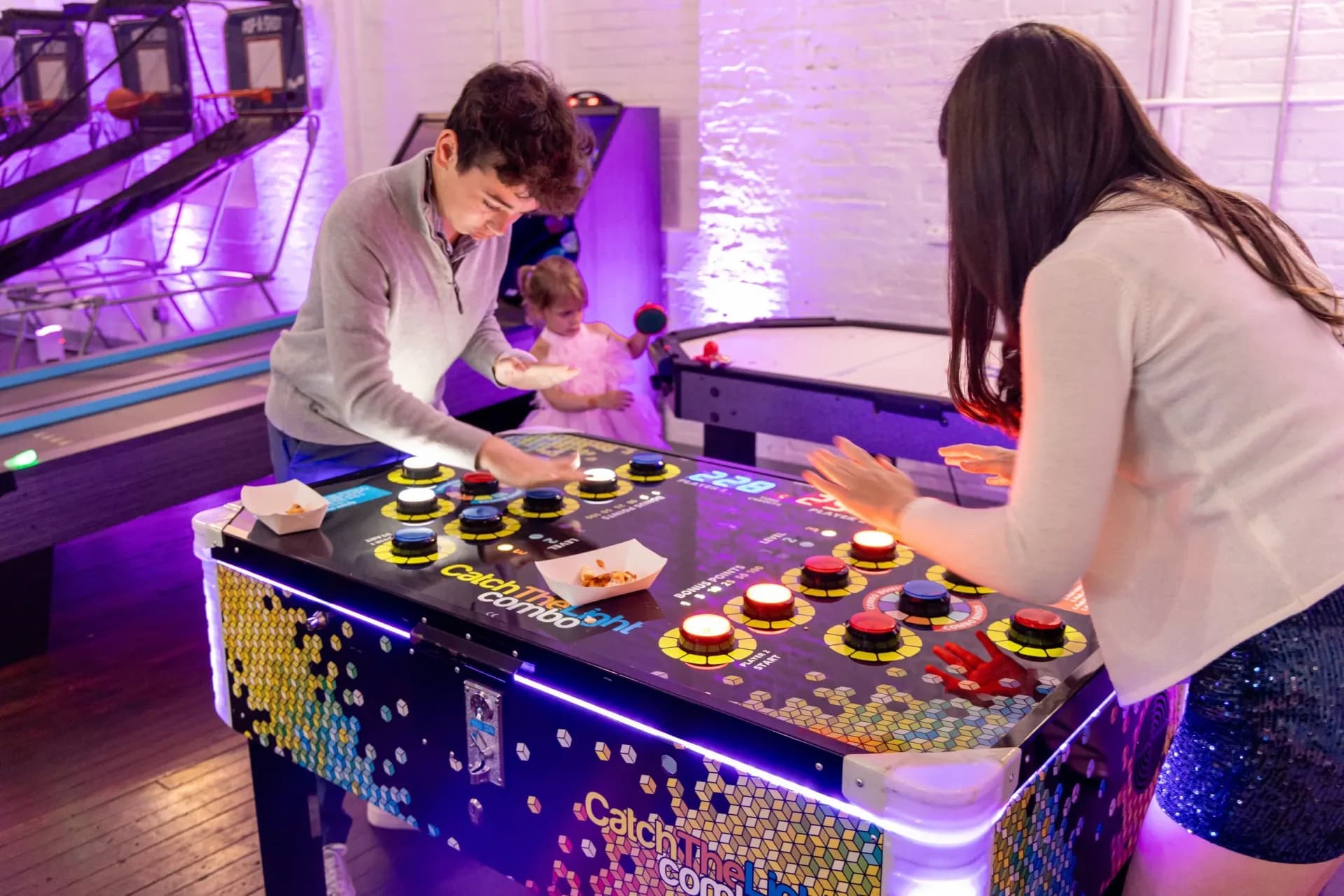Catch the light LED reflex game at an event, two players tapping backlit reaction buttons across the glowing platform