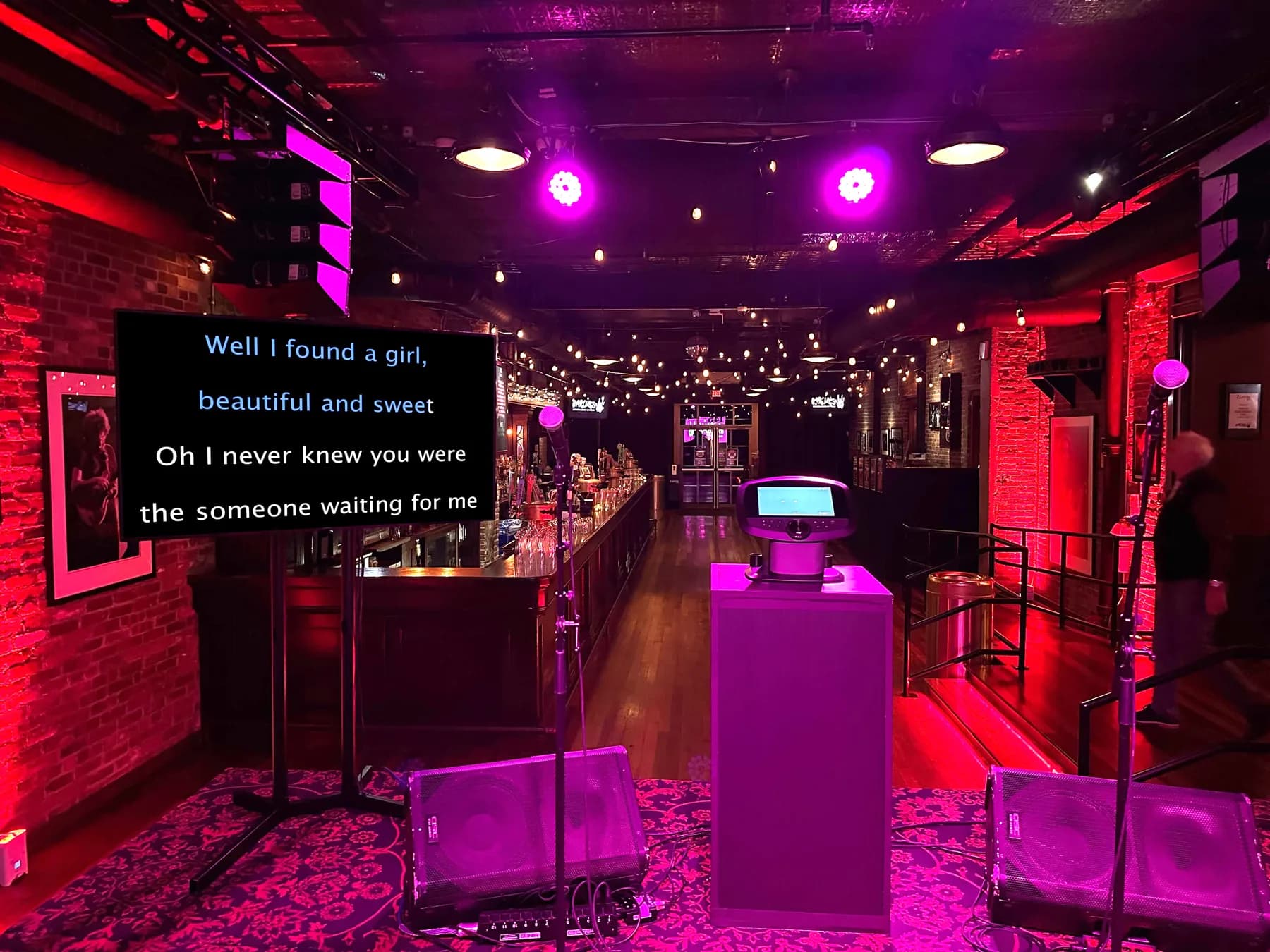 Classic karaoke setup at a bar mitzvah or corporate event, guest performing live on stage with lyrics displayed on a large screen