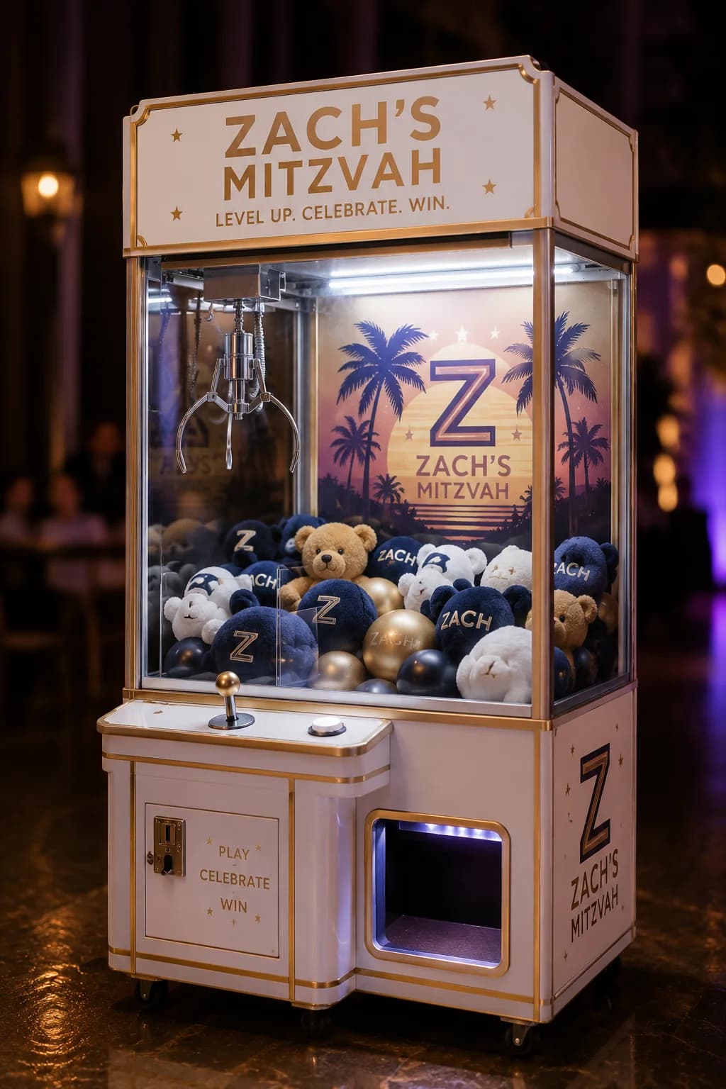 Prize crane claw machine event rental with a custom-branded white and gold cabinet stocked with branded plush prizes, a classic arcade grab game for mitzvahs and corporate events