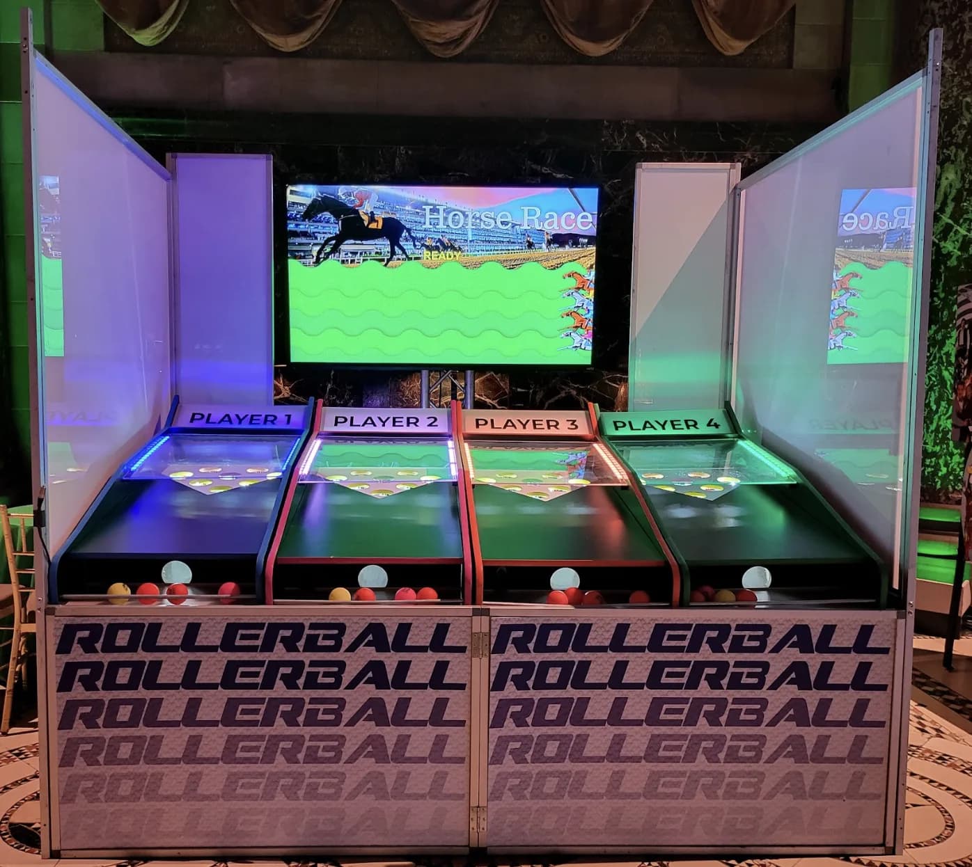 Roller ball game rental with four player lanes and an 80-inch screen showing a character race at an event in NYC