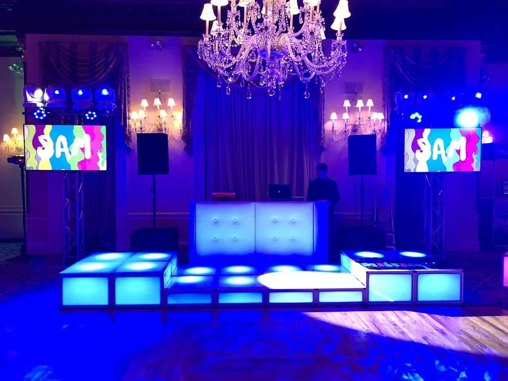 A custom bar mitzvah stage with chandeliers and LED light bars by Nicholson Events