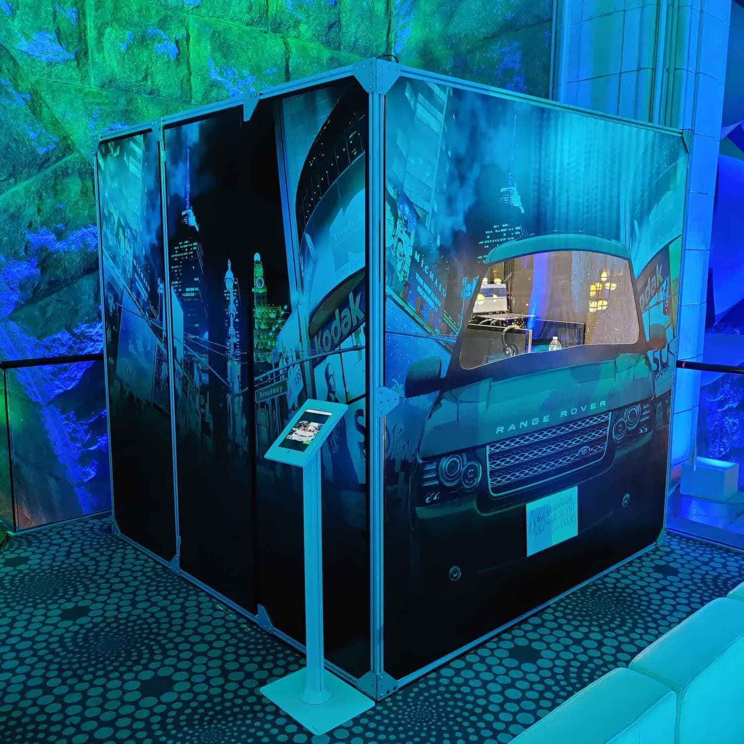 Closed enclosed car singing booth with city mural wrap under dramatic blue and green event lighting