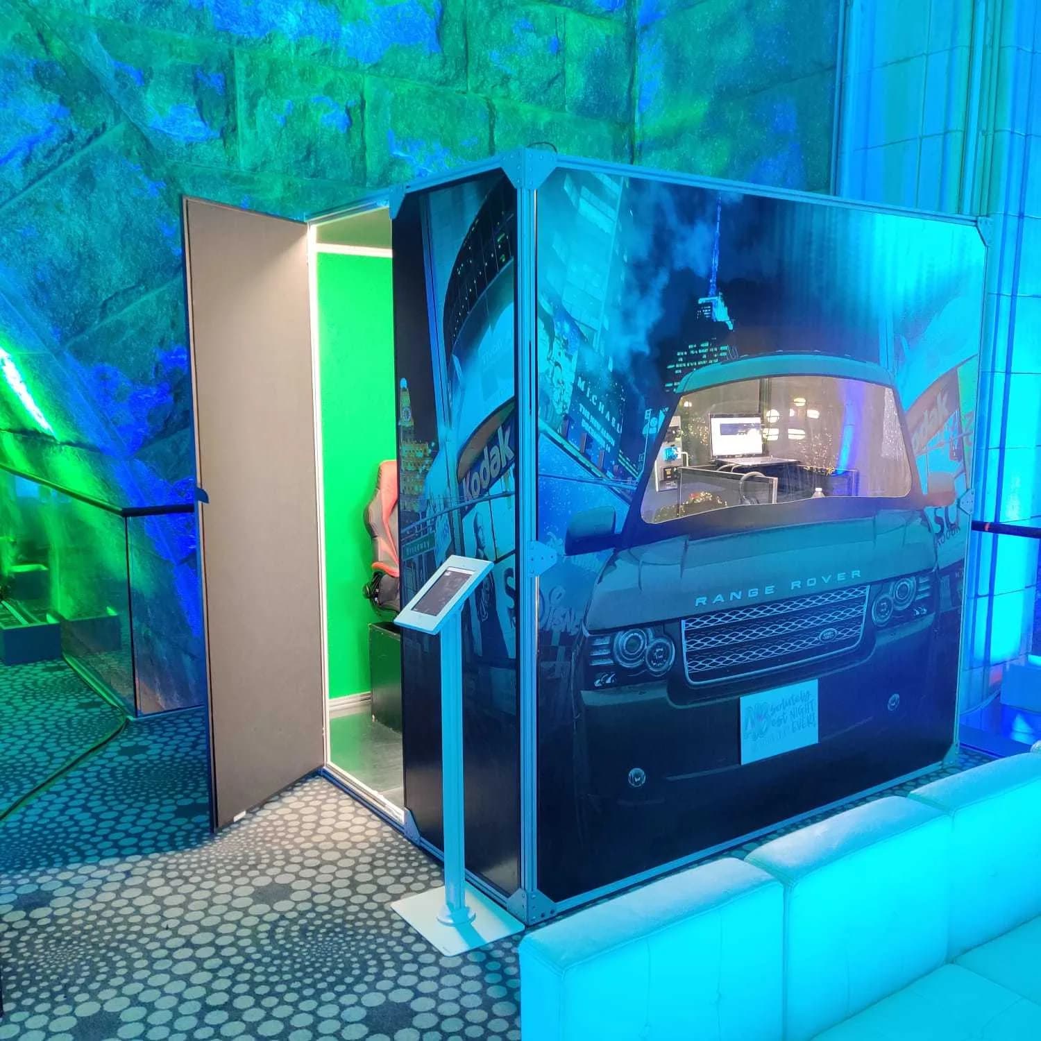 Car booth door open revealing green screen interior and racing seats inside the enclosed singing booth