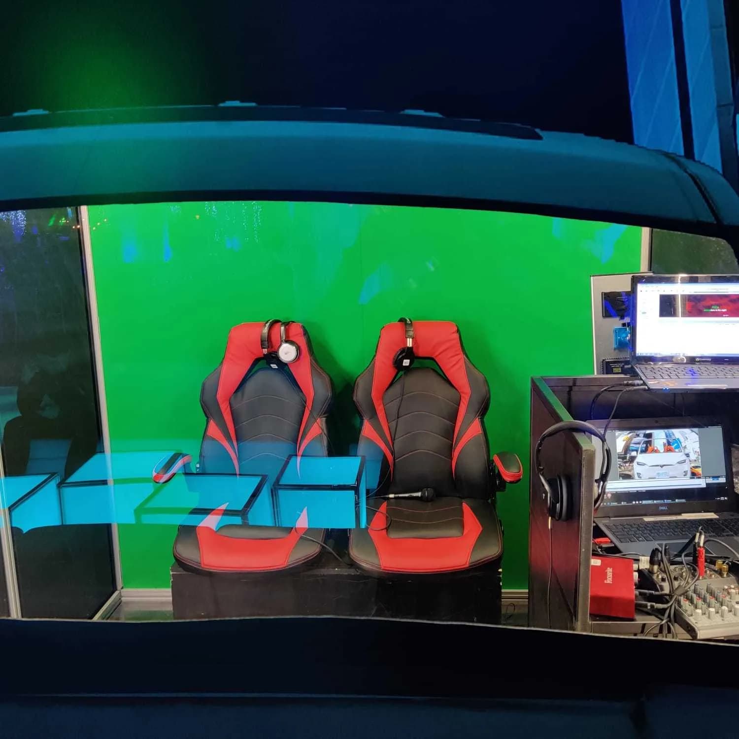 Interior of enclosed car booth with red racing seats and green screen background ready for a singing performance