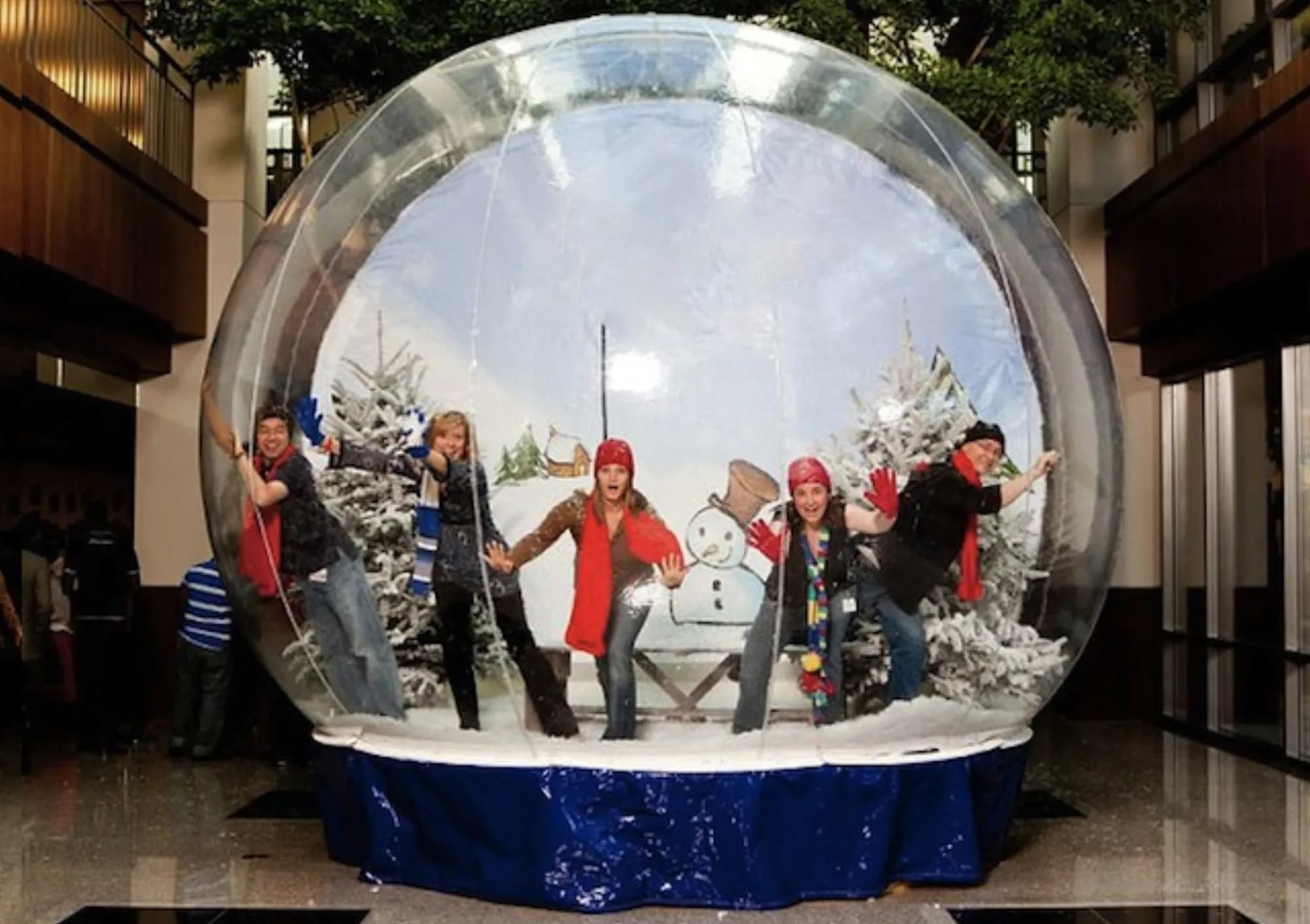 Guests inside a giant illuminated snow globe at a holiday party