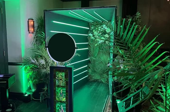 Glam photo booth neon green tropical backdrop setup with ring light at an event