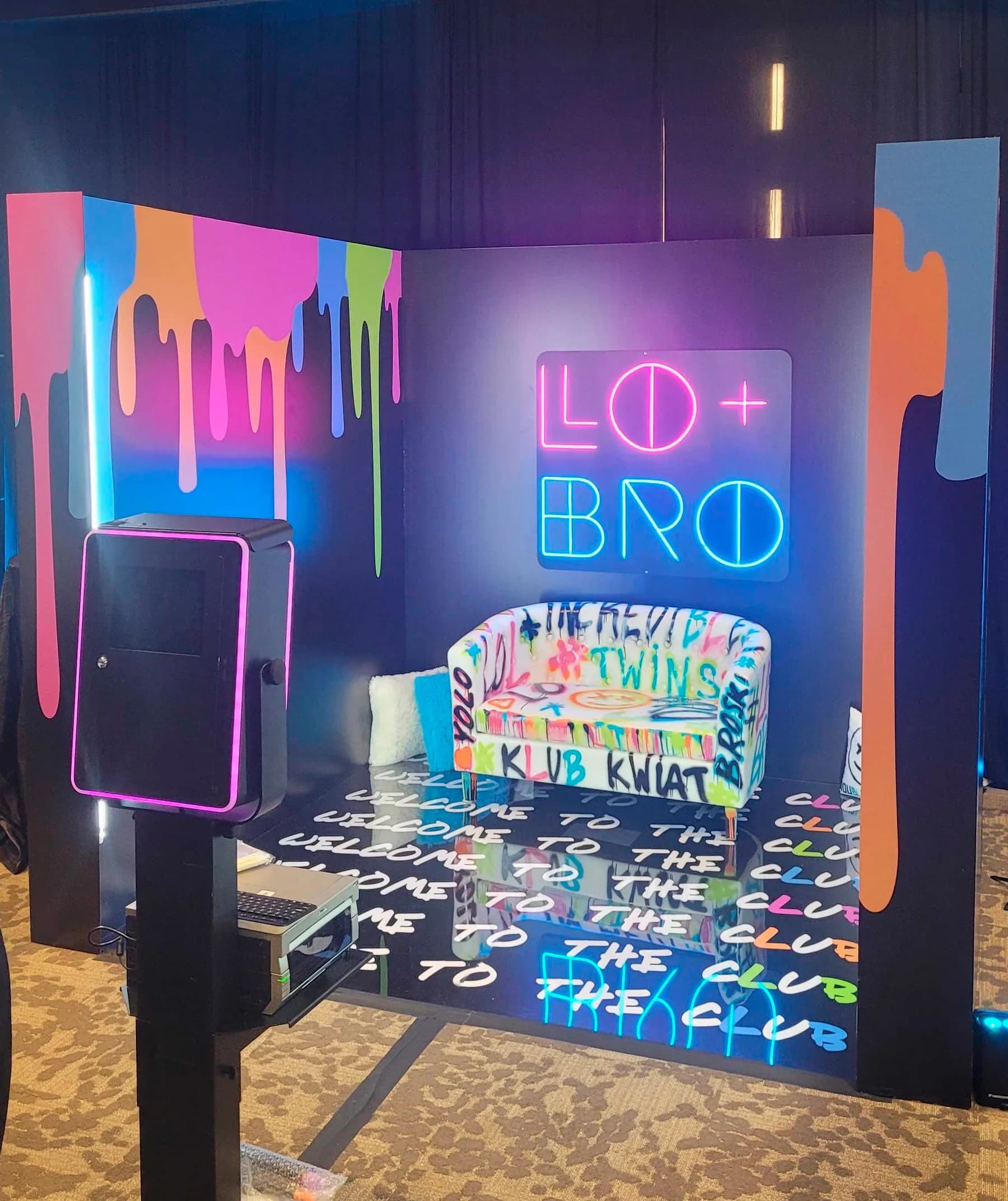 Colorful paint-drip immersive photo booth interior with neon signage and custom graffiti-style wall decor at a party