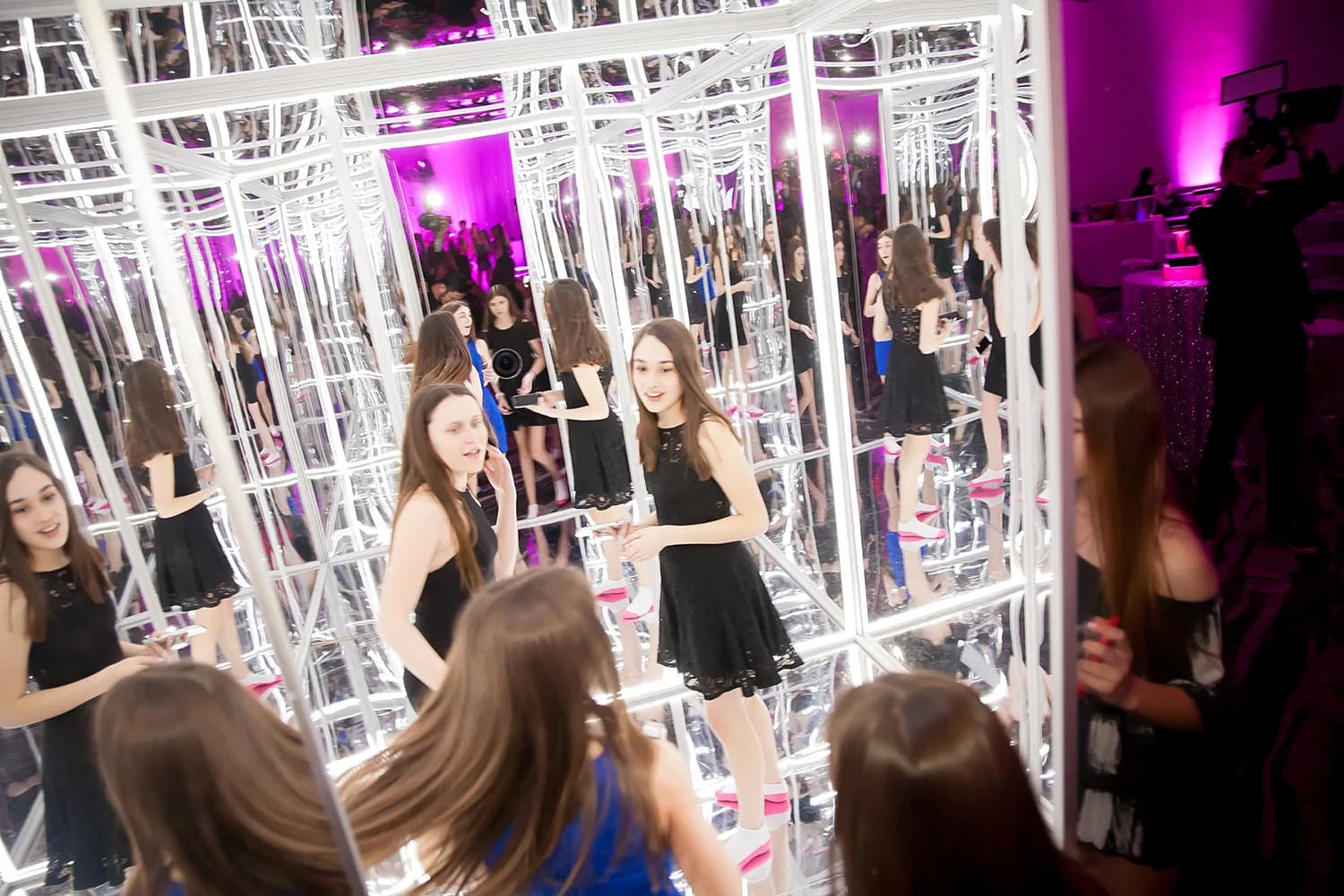 Inside view of the infinite mirror room with guests surrounded by endless reflections and pink ambient lighting at a mitzvah
