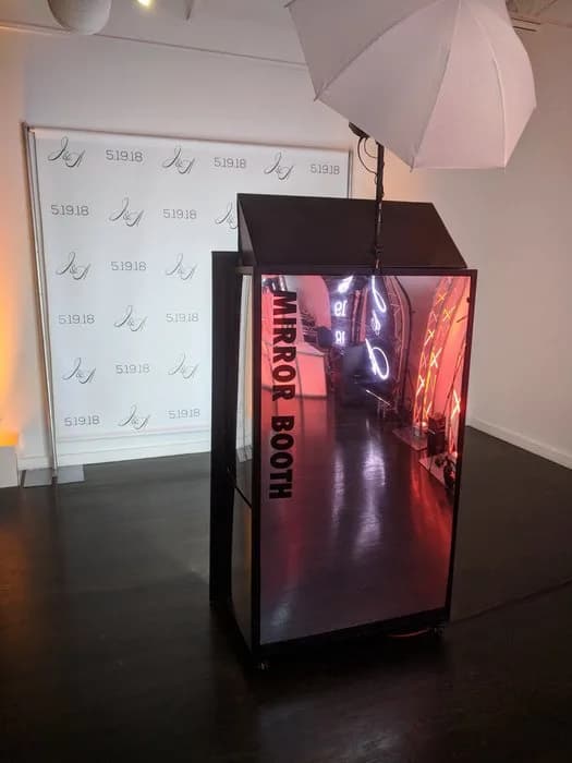 Mirror photo booth open showing LED neon interior lighting glow at a live event
