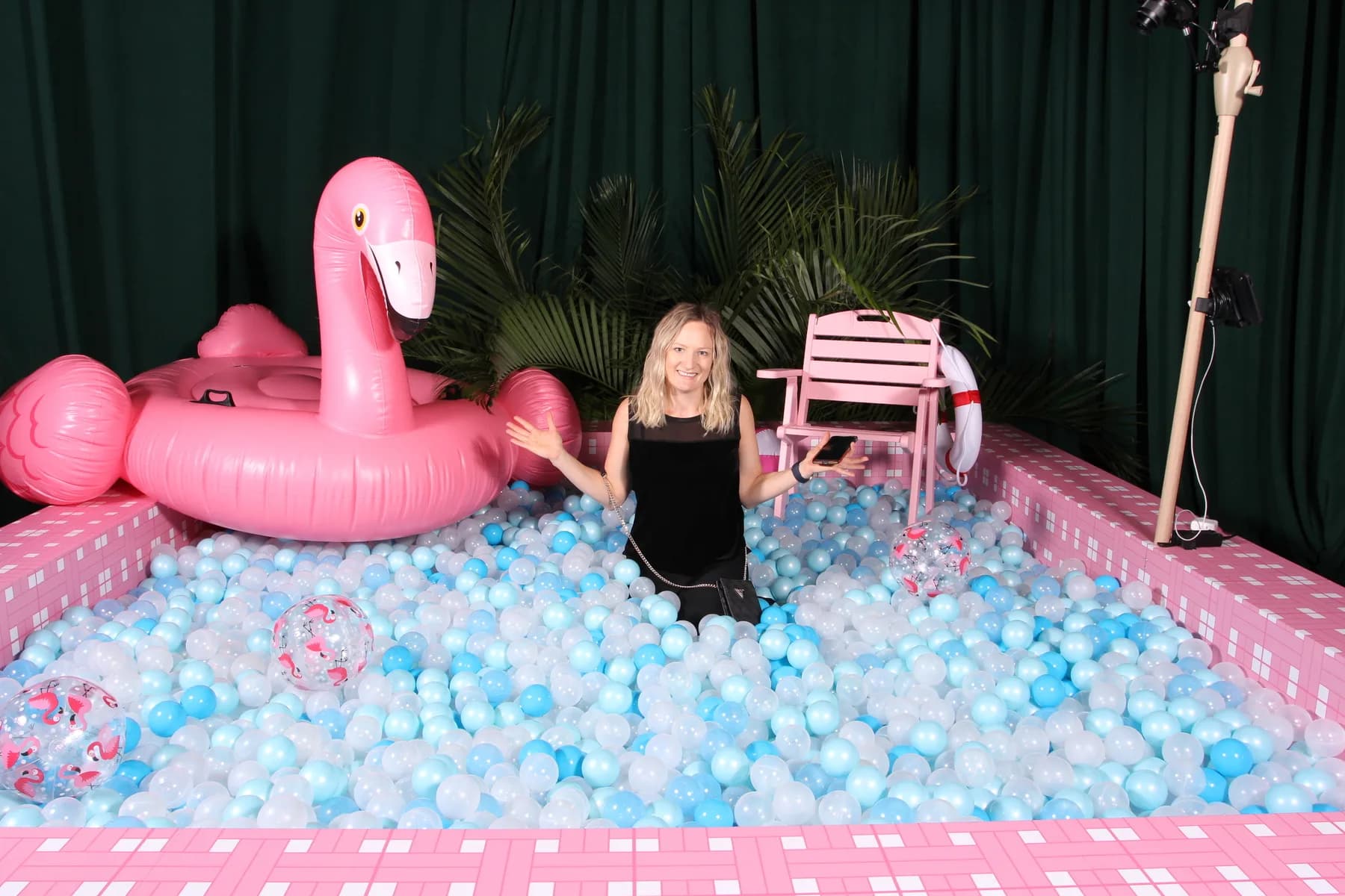 Guest playing in a large adult ball pit with flamingo float and tropical decor at a celebration event