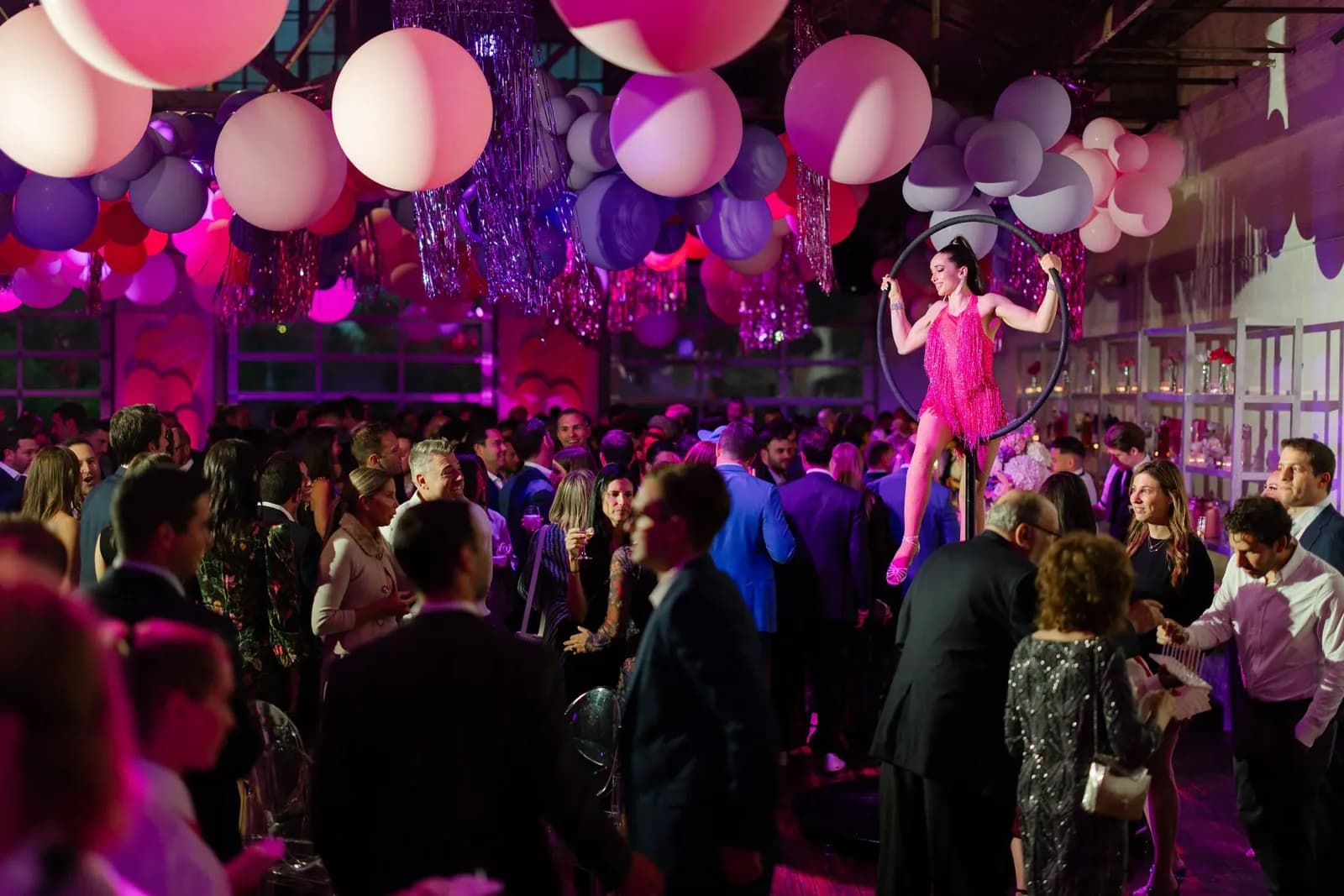 Packed fundraiser gala with an aerialist performing on a lyra hoop under a balloon installation in the Boathouse at The Knowlton in Bridgeport, CT
